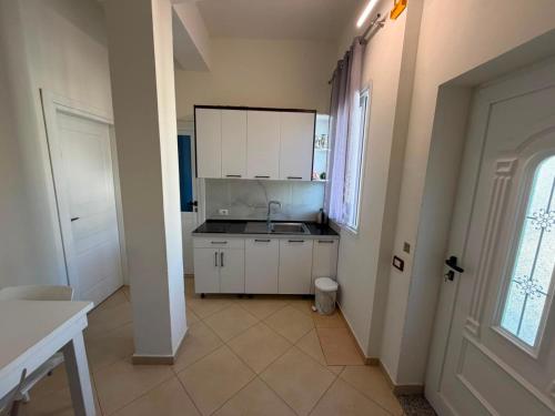 a small kitchen with white cabinets and a sink at Vila Olti in Vlorë