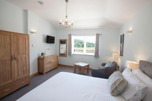 Mincombe Barn Bed & Breakfast في Sidbury: غرفة نوم بسرير وكرسي ونافذة