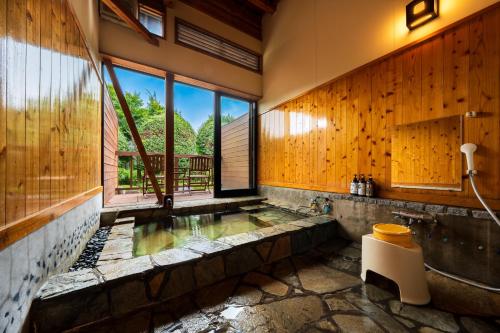 a bathroom with a hot tub with wooden walls at Okuyado Buaiso in Yufu