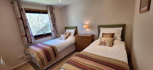 two twin beds in a room with a window at Caisteal Liath Chalets in Lochinver