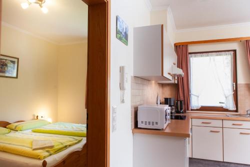 a small kitchen with a bed and a microwave at Haus Keller Ferienwohnungen in Todtnauberg