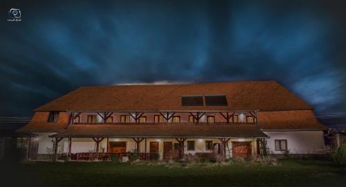 a large house with a brown roof on a field at Kúria Vendégház in Cristuru Secuiesc