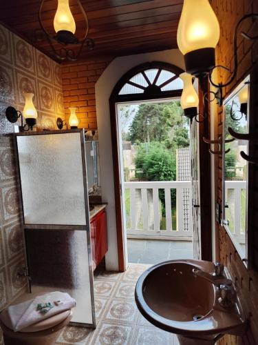 a bathroom with a sink and a door to a porch at Refugio maná in Campos do Jordão