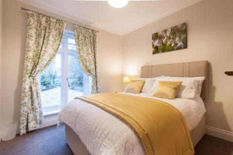 Un dormitorio con una cama grande y una ventana en Milntown Self Catering Apartments, en Ramsey