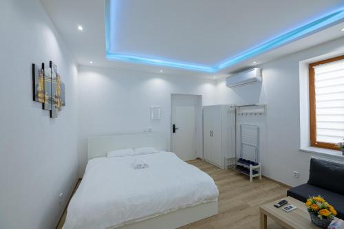 a white bedroom with a bed and a couch at L&S House in Prague