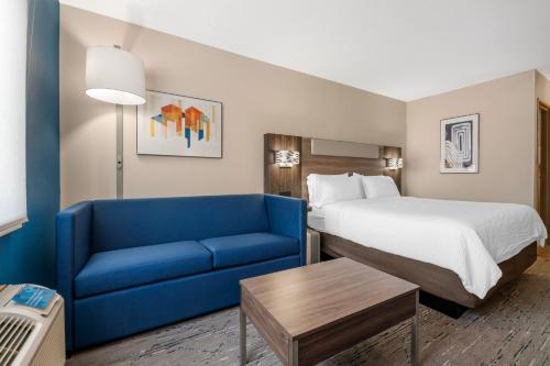 a hotel room with a bed and a blue couch at Holiday Inn Express Deforest Madison Area by IHG in De Forest