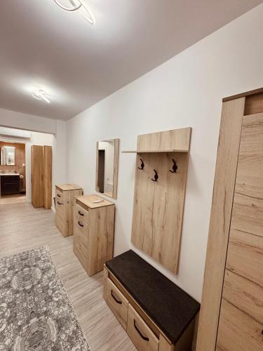 a dressing room with wooden cabinets and a bench at A B V Central Apartment- Unitate autorizata de Ministerul Turismului in Râmnicu Vâlcea