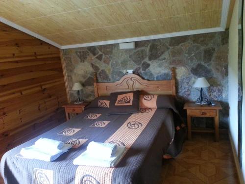 a bedroom with a bed in a log cabin at Hostal La Collada de Aralla in Aralla de Luna