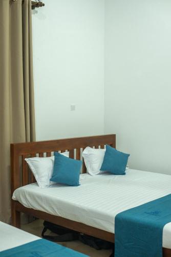 a bed with blue and white pillows on it at Villa Downsouth Nilaveli in Kumpurupiddi