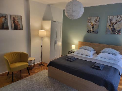 a bedroom with a large bed and a chair at Tornyai Apartman in Hódmezővásárhely