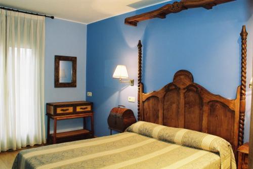 a bedroom with a wooden bed and a blue wall at Hotel Conventin in Villaviciosa