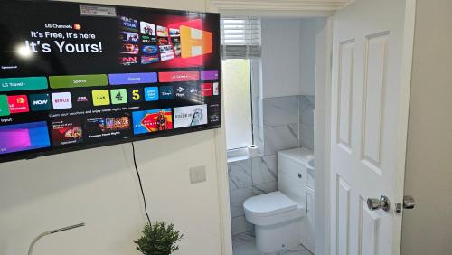 a bathroom with a toilet and a tv on the wall at New Horizon Lodge in Leigh