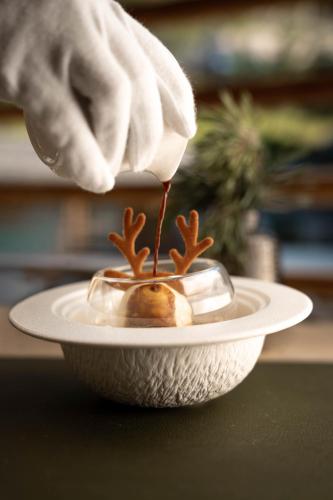 a person is drizzling sauce onto a bowl at Presulis Hideaway Apartments & Restaurant in Völs am Schlern
