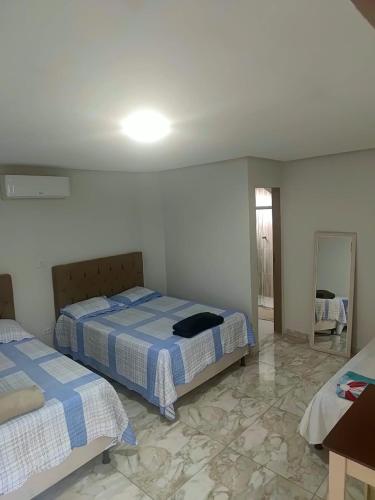 a bedroom with two beds and a mirror in it at Hotel Boneario in Vitória da Conquista