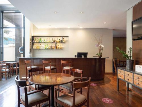 a restaurant with a table and chairs and a bar at Mercure Sao Paulo Paulista in São Paulo