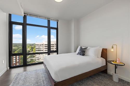 a bedroom with a white bed and a large window at Placemakr Marymount Ballston in Arlington