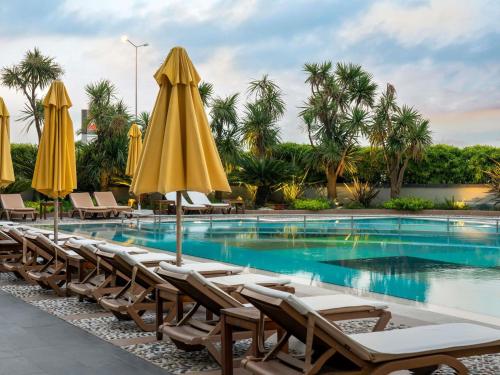 a swimming pool with lounge chairs and umbrellas at Novotel Istanbul Zeytinburnu in Istanbul