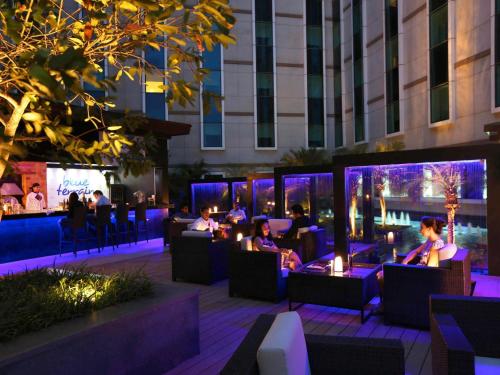 a group of people sitting in a restaurant at night at Novotel Bengaluru Outer Ring Road in Bangalore