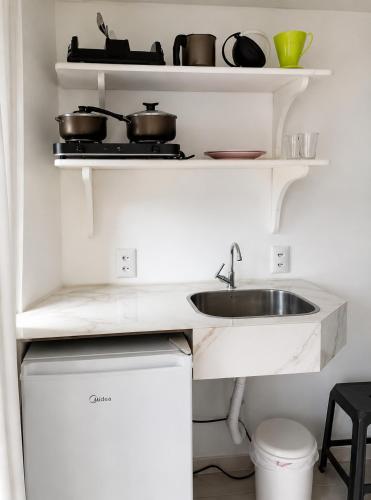 a kitchen with a sink and shelves with pots and pans at Pousada Cristais do Rosa in Imbituba