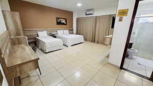 a hotel room with two beds and a bathroom at Aldeias Palace Hotel in Tucuma