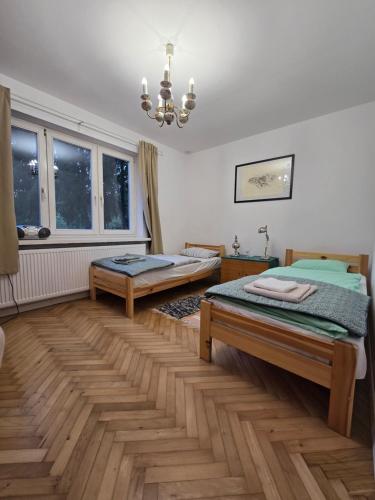 a bedroom with two beds and a chandelier at Augustówka - letnisko na Wrzosowiskach in Mostówka