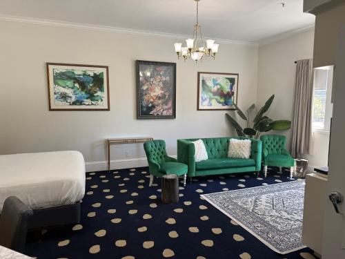 a hotel room with a bed and two green chairs at The Sterling Hotel in Sacramento