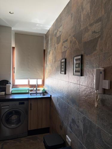 a bathroom with a sink and a washing machine at Ático Santa Lucía Terraza y Parking gratuitos in Alcalá de Guadaira