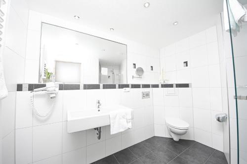 a white bathroom with a sink and a toilet at Hotel Zum grünen Kranz in Zell an der Mosel