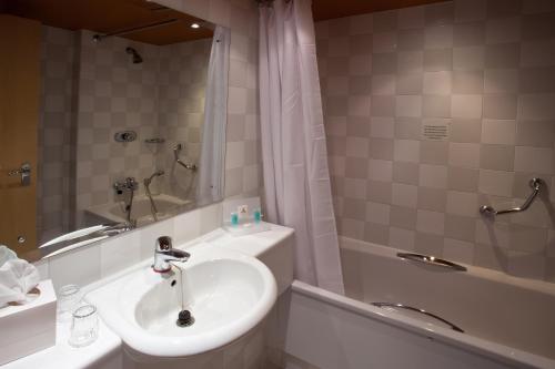 博爾頓的住宿－大不列顛博爾頓酒店，浴室配有水槽、淋浴和浴缸。