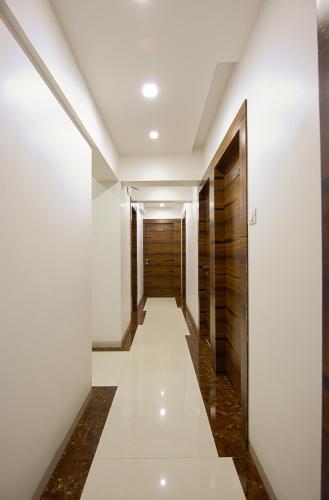 a hallway with white walls and a wooden door at Hotel Fantacee in Navi Mumbai