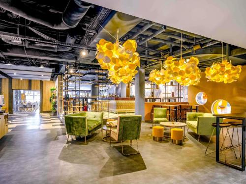 a room with yellow chairs and tables and chandeliers at Ibis Styles Regensburg in Regensburg