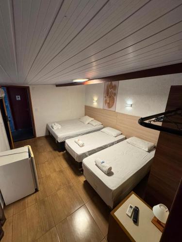 a hotel room with three beds and a table at Flamingo Beach Pousada in Cabo Frio
