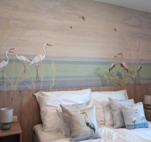 a painting of birds on a wall above a bed at Levendula Apartman in Buzsák