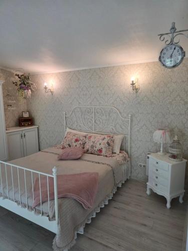a bedroom with a white bed and a clock on the wall at Holiday Home Kolka in Kolka