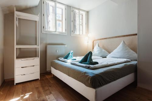 a bedroom with a bed with a dresser and windows at Boutique Apartment QLB est 1688 in Quedlinburg