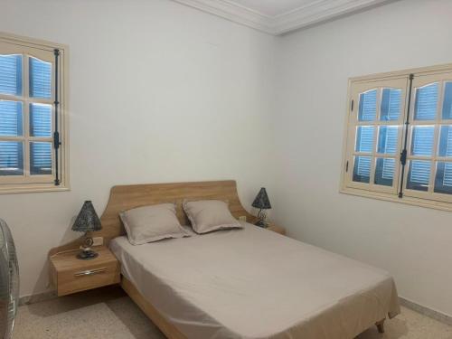 a bedroom with a bed and two windows at Résidence Djerba Oasis in Mezraya