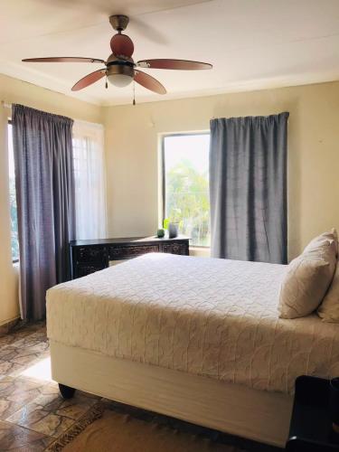a bedroom with a bed and a ceiling fan at Glenmore Sea View Appartments in Leisure Crest