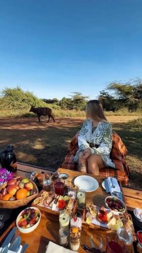 a woman sitting on a table with plates of food at Olopiro Stay in Maasai Mara National Reserve
