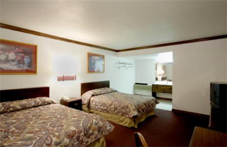 a hotel room with two beds and a television at Executive Inn Muldrow in Muldrow