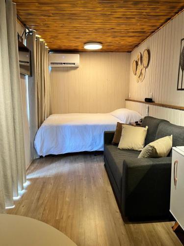a bedroom with a bed and a couch in a room at Cabana ECO - Teresópolis in Teresópolis