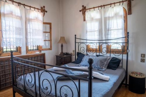 a bedroom with a wrought iron bed with blue pillows at Pietra Mare Suites Villa in Palaión Eleftherochórion