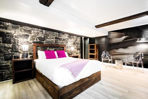a bedroom with a large bed and a stone wall at C3- Hotel Art De Vivre in Quebec City