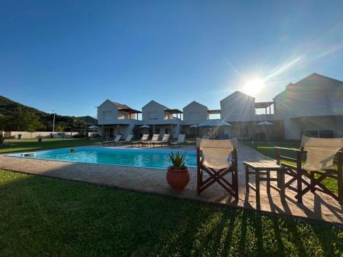 a house with a pool and two chairs and a table at Dimis Luxury Suites in Paralia Sikias