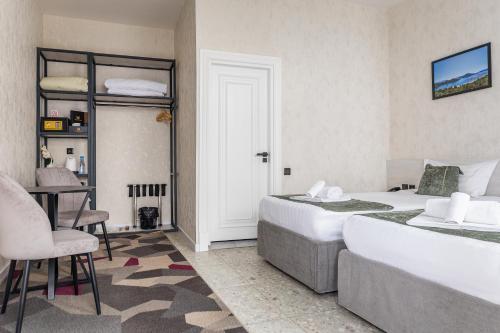 a bedroom with two beds and a table and a chair at Marmaris Saray Hotel DOWNTOWN in Tashkent