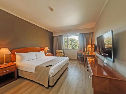 a hotel room with a bed and a television at Hotel Agua del Desierto in Calama