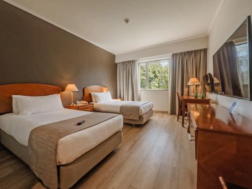 a hotel room with two beds and a desk at Hotel Agua del Desierto in Calama