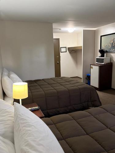 a hotel room with two beds and a lamp at Minnedosa Inn in Minnedosa