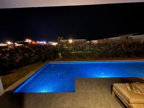 a blue swimming pool at night with flowers at SeaBreeze White Villa 42 in Nardaran