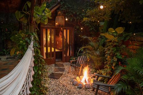 a fire pit in a garden with a hammock at Chalés Magia do Campeche in Florianópolis