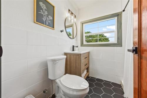 a bathroom with a toilet and a sink and a window at Cedar Nest - Lakefront Cabin Retreat in Madill